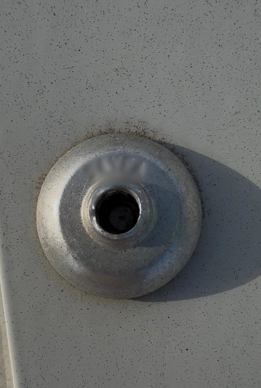 Close-up of a failed rivet on a roof anchor base plate, stem sunk deep inside the head