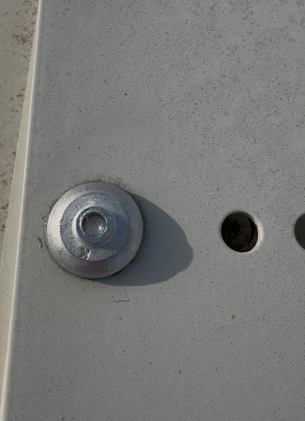 Close-up of a correctly set rivet on a roof anchor base plate, stem sitting near the top of the head