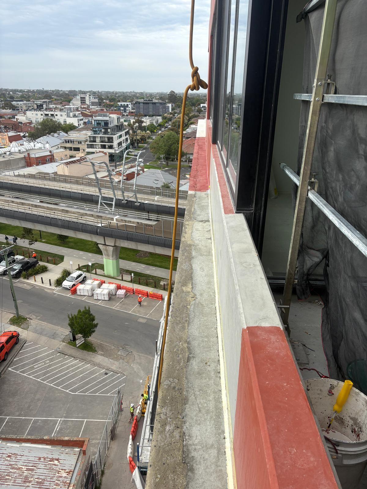 Facade capping repairs high above street and rail line from ropes, Carnegie