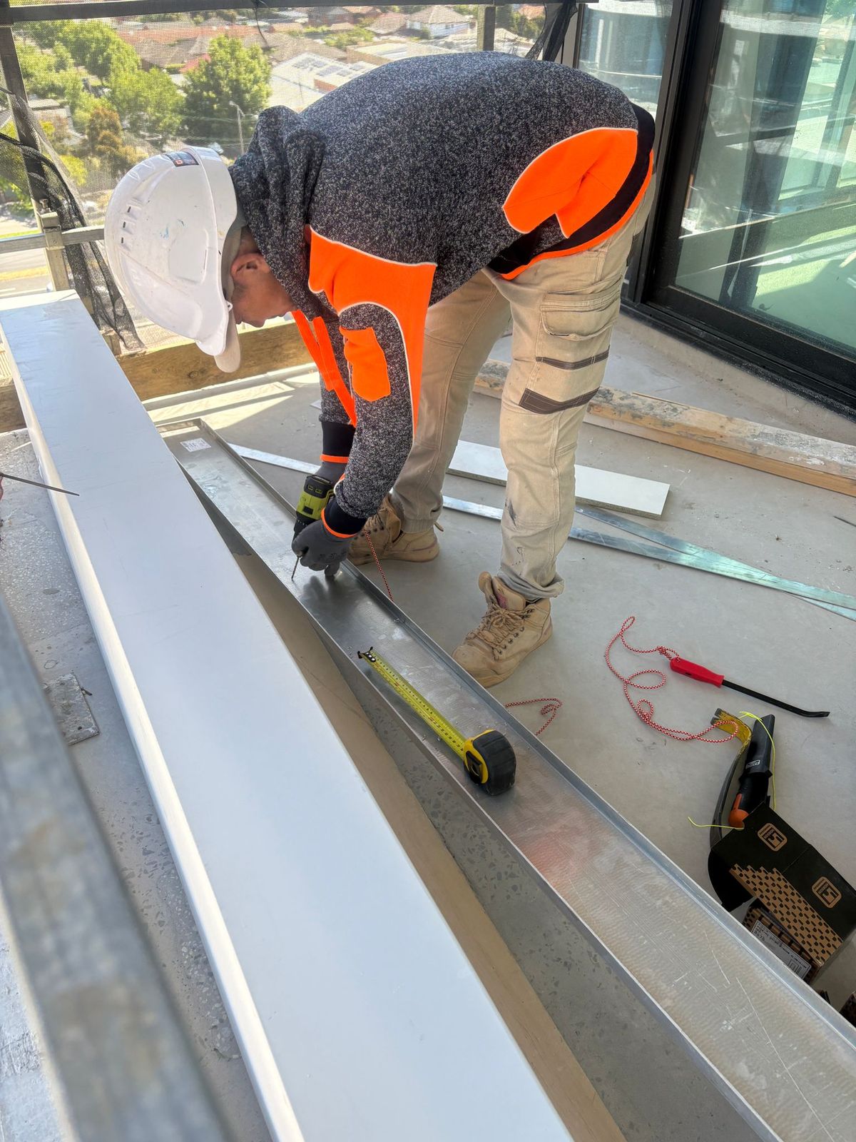 Technician cutting flashing for slab edge facade repair, Melbourne