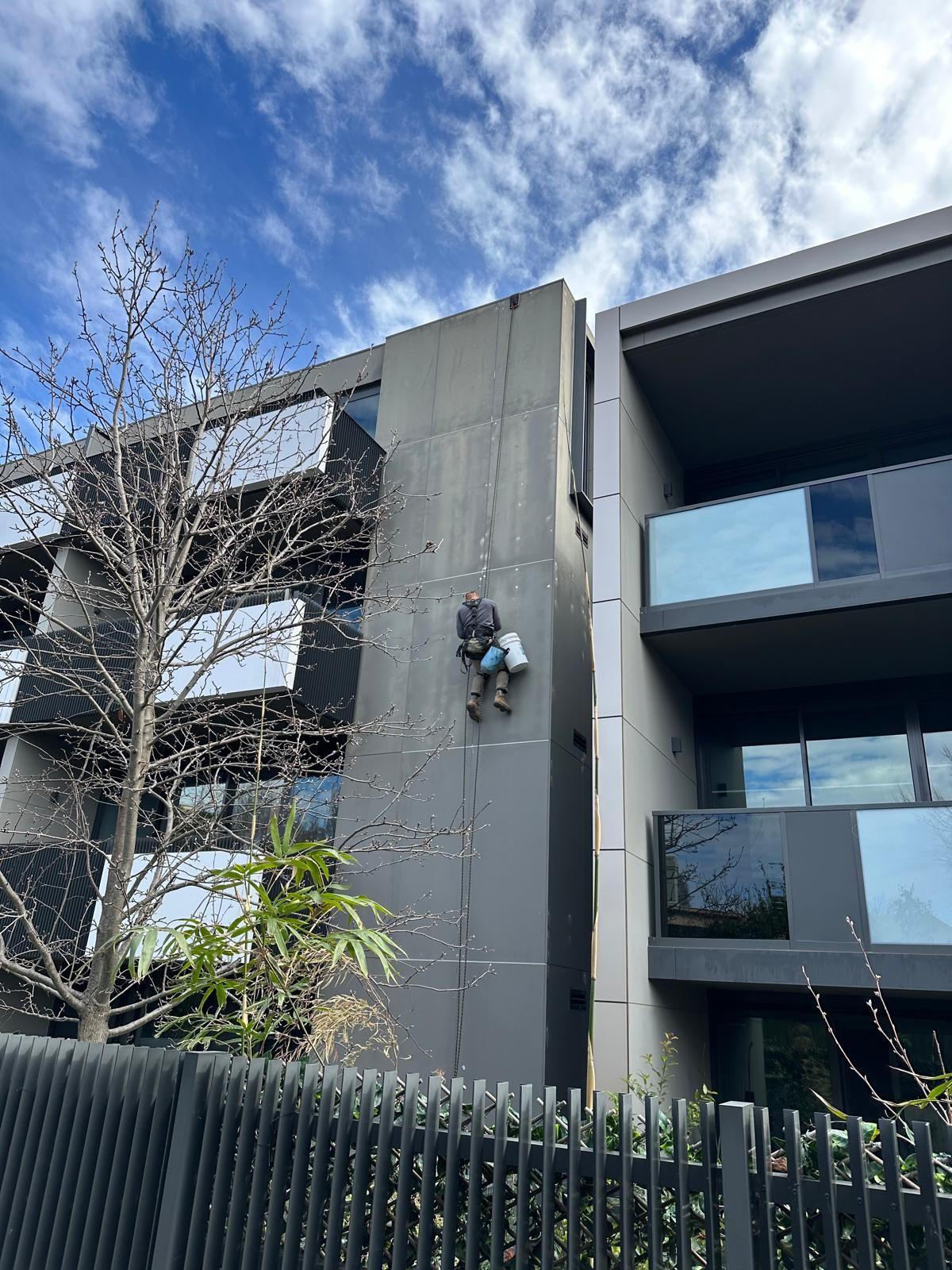 Rope access technician repairing apartment building facade in Melbourne, no scaffolding