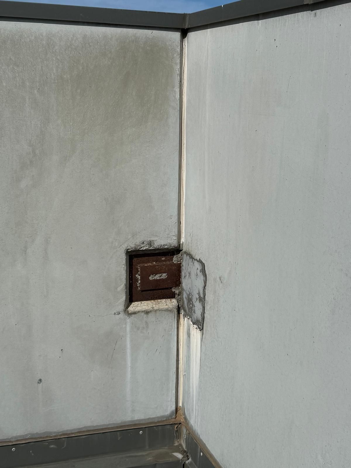 Rusting steel stitch plate at precast panel corner with efflorescence running down the joint below, Melbourne